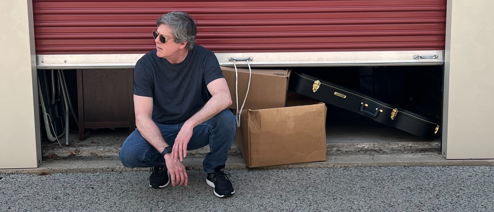 Bill Gallagher outside his storage unit with a guitar case